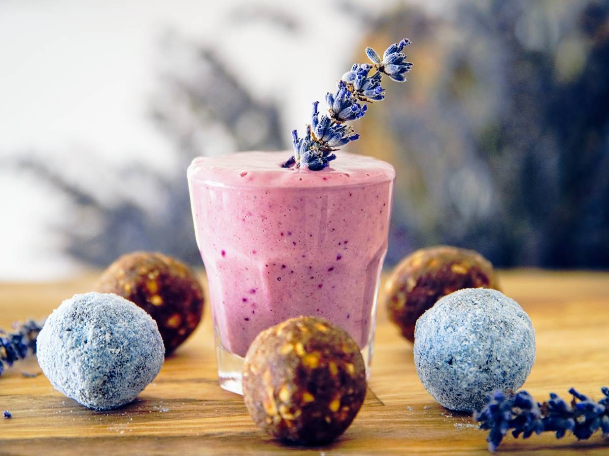 Malteada rosada en un vaso de vidrio, con bolitas de frutos secos y ramitas de lavanda